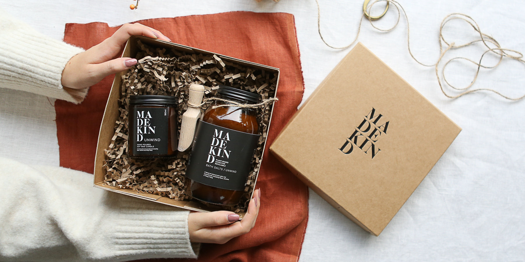 Women opening gift box with aromatherapy bath salts and soy wax candle for Christmas gifting