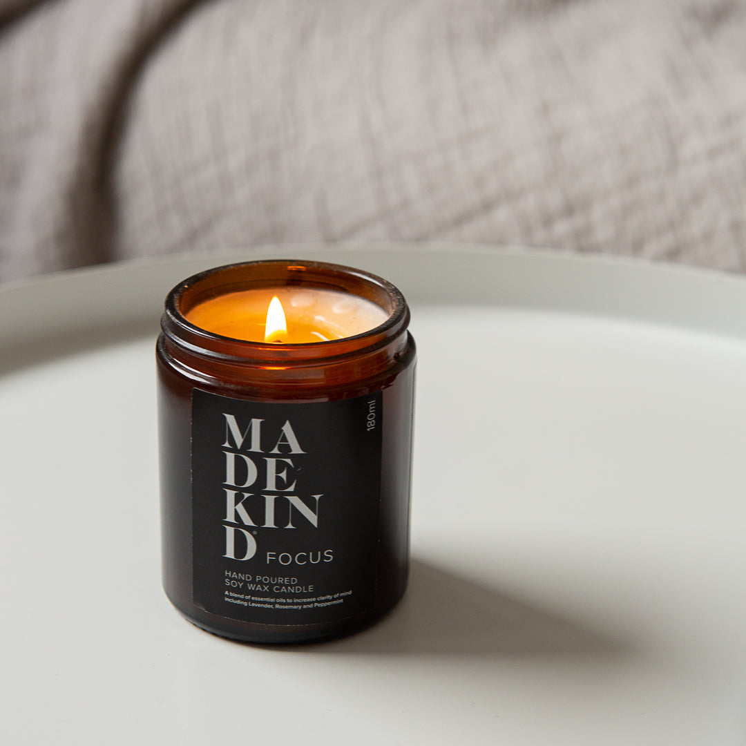 Photo of a lit MadeKind candle in amber glass jar