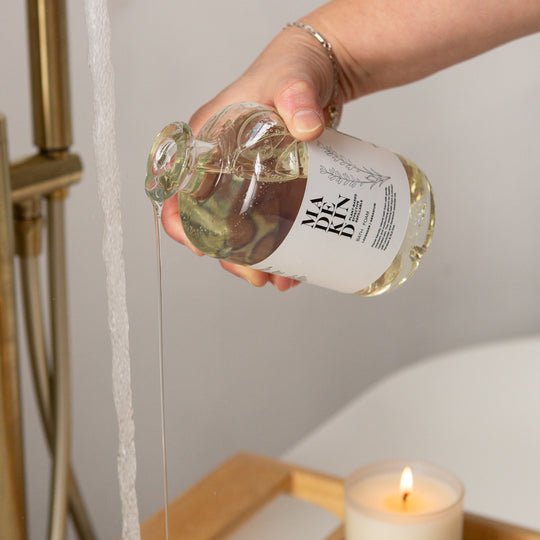 Hand holding a bottle of MadeKind Bath Foam being pured into a bath