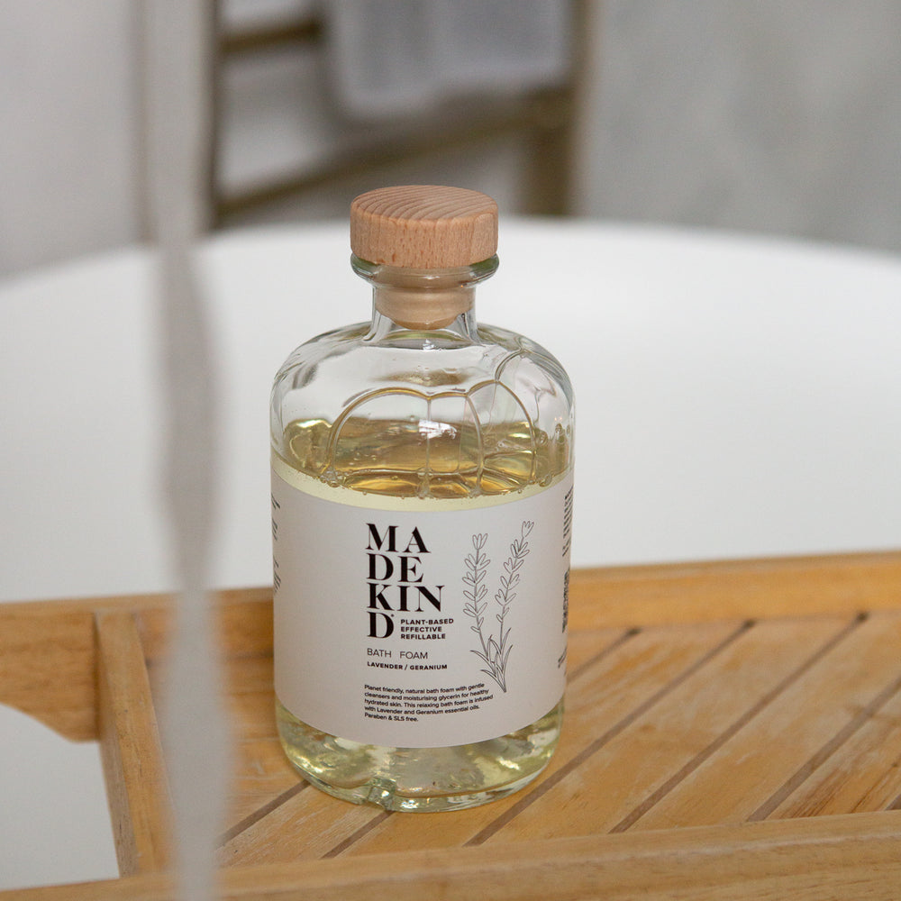 Bottle of Madekind Bubble bath on a wooden surface with a blurred background in a bathroom