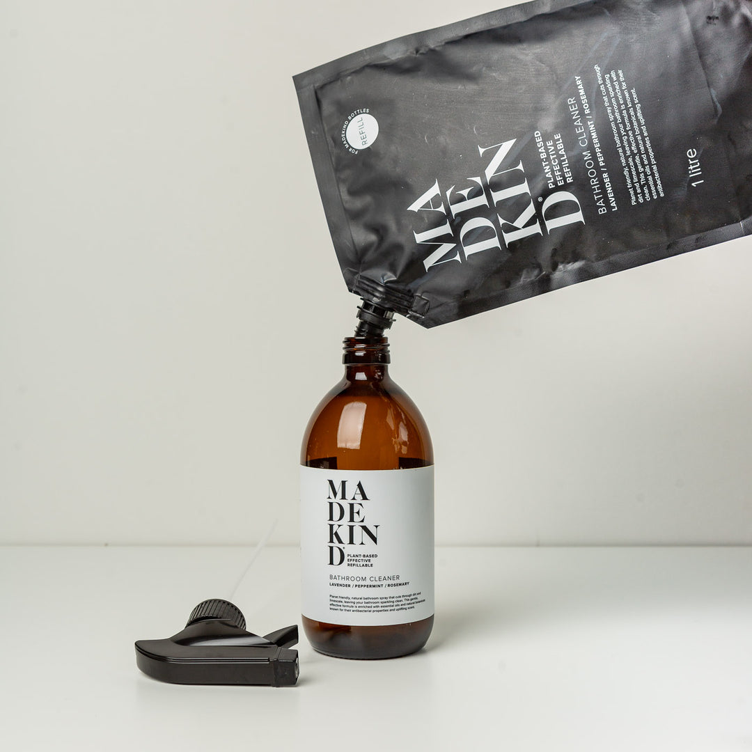 Photo of MadeKind Bathroom Cleaner refill pouch being poured into a MadeKind Bathroom Cleaner amber glass bottle