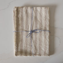 Load image into Gallery viewer, Photo of a woven line beige and white striped tea towel, folded and tied with twine
