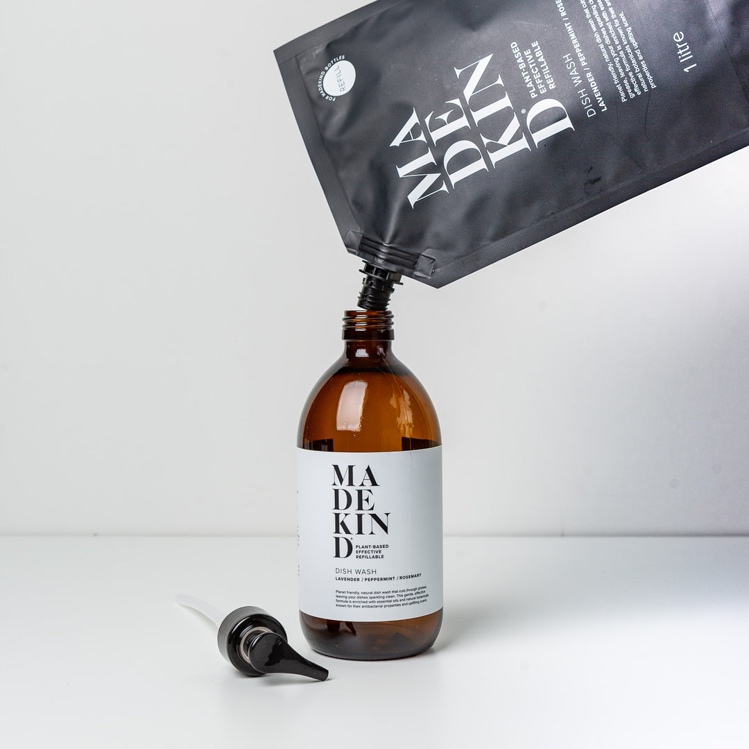 Eco friendly refillable glass bottle with MadeKind cleaning products being poured from a refill pouch.