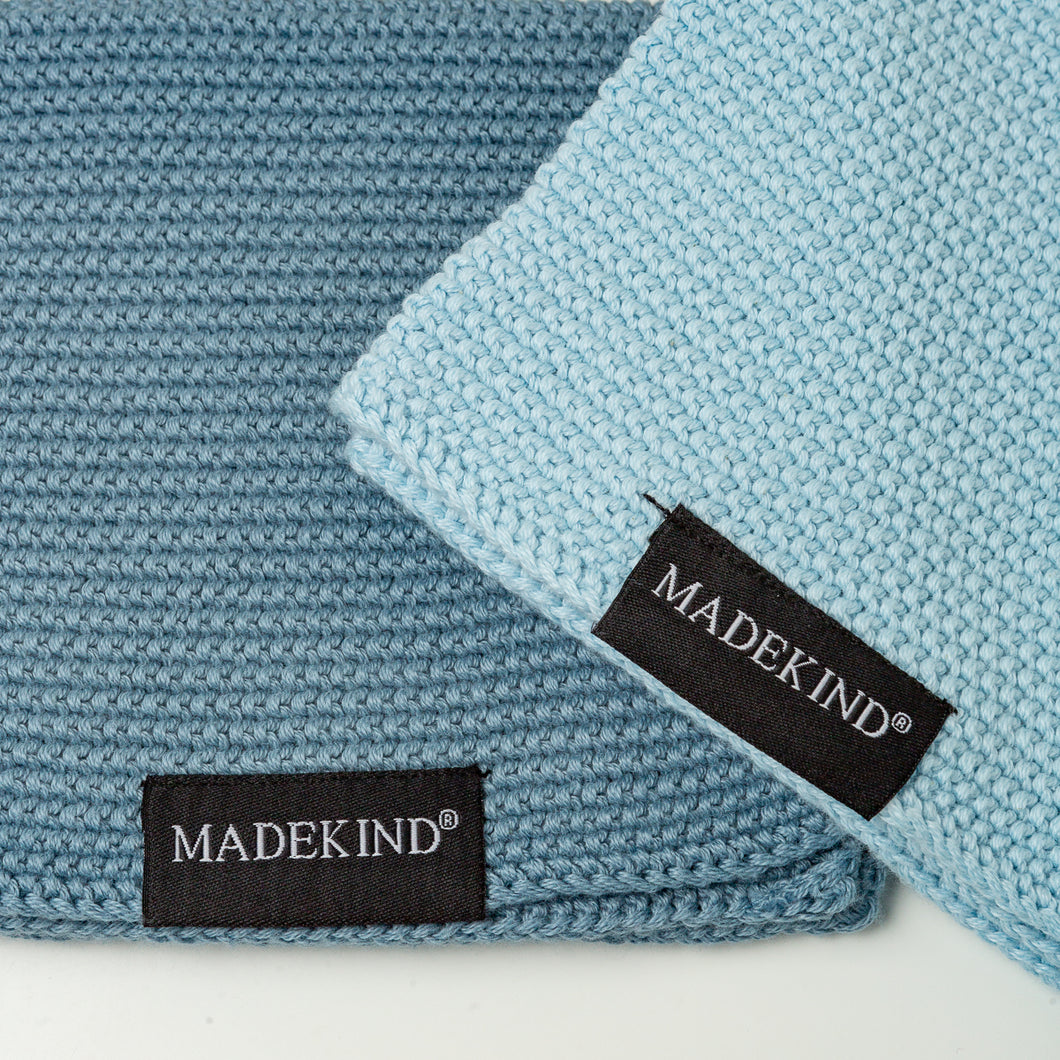 Photo of two blue madekind cloths with the logos on the front