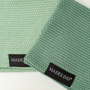 Photo of two green madekind cloths with the logos showing