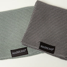 Load image into Gallery viewer, Photo of two grey madekind cloths with the logos showing
