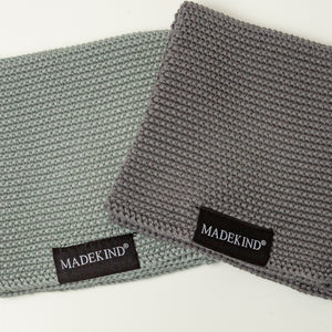 Photo of two grey madekind cloths with the logos showing