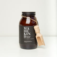 Load image into Gallery viewer, Photo of an amber glass jar of MadeKind bath salts with a wooden scoop
