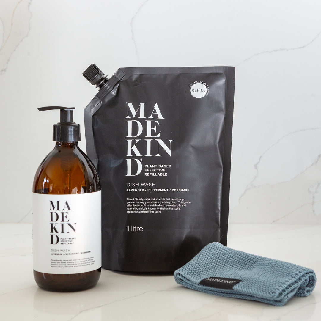 Made Kind dish wash bottle, refill pouch, and blue cloth on a marble background