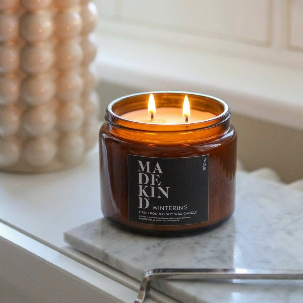 Three wick MadeKind Soy Wax Candle in Amber Glass jar on window ledge. 