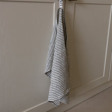 Load image into Gallery viewer, Photo of a woven linen grey striped tea towel hanging from a hook in a kitchen
