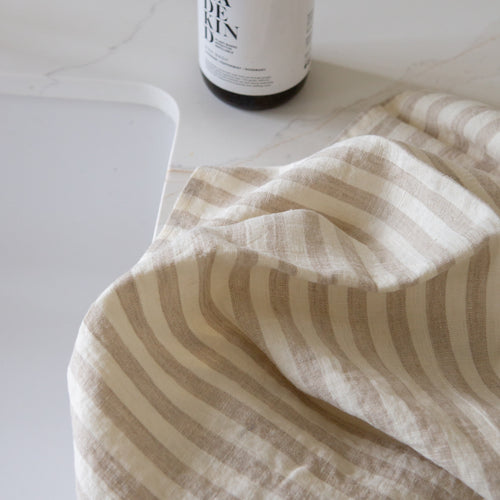 Photo of a beige and white woven linen tea towel next to a kitchen sink