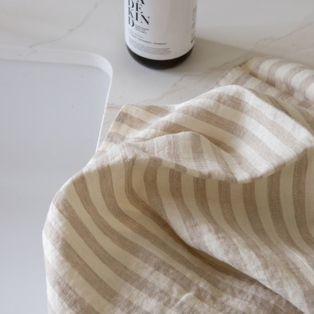 Photo of a beige and white woven linen tea towel next to a kitchen sink