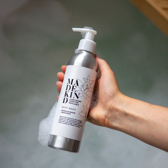 Photo of a hand holding a MadeKind body wash bottle