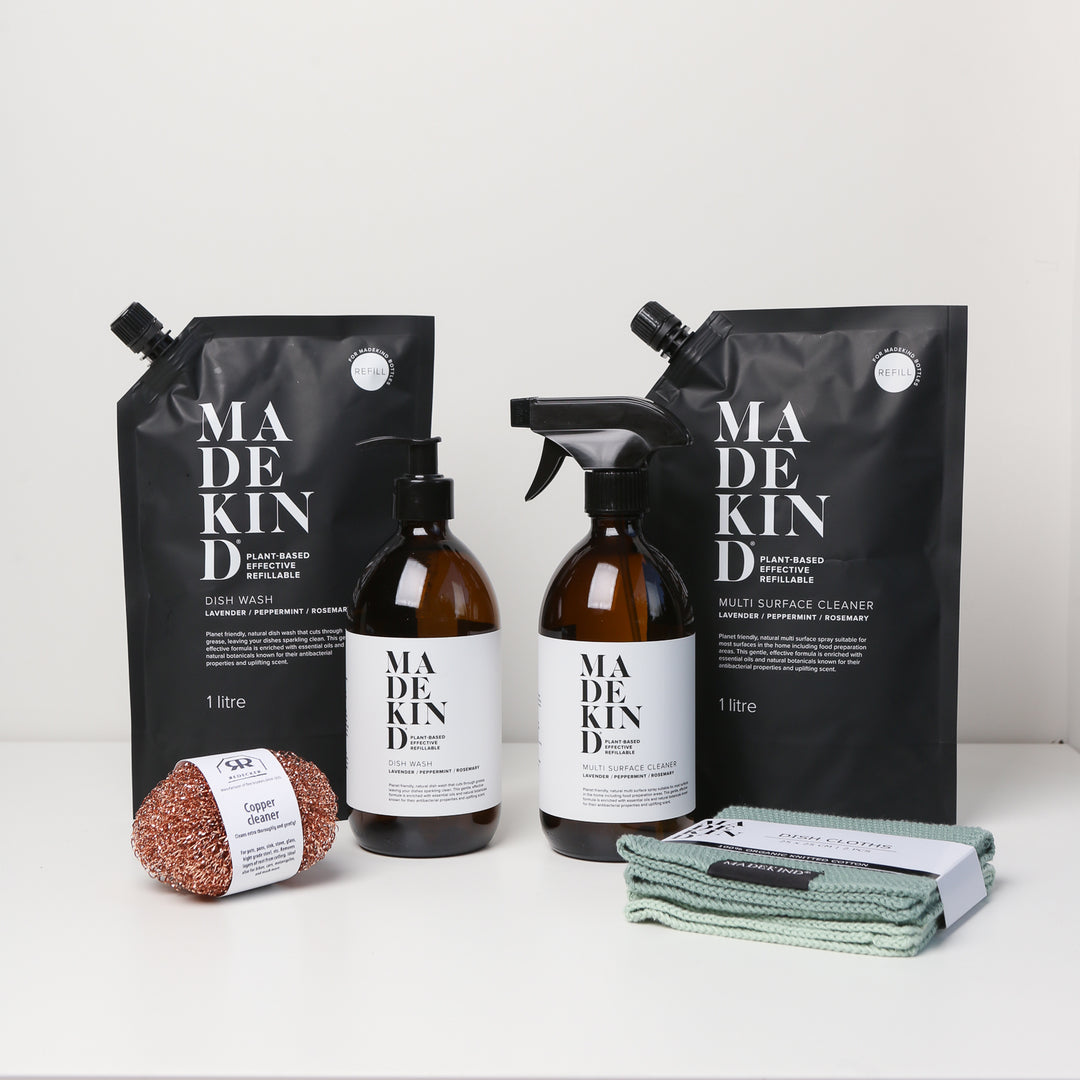 Photo of the MadeKind Kitchen Cleaning Kit; Multi Surface Cleaner and Dish Wash refills with 2 empty amber glass bottles, copper scourers and green dishcloths