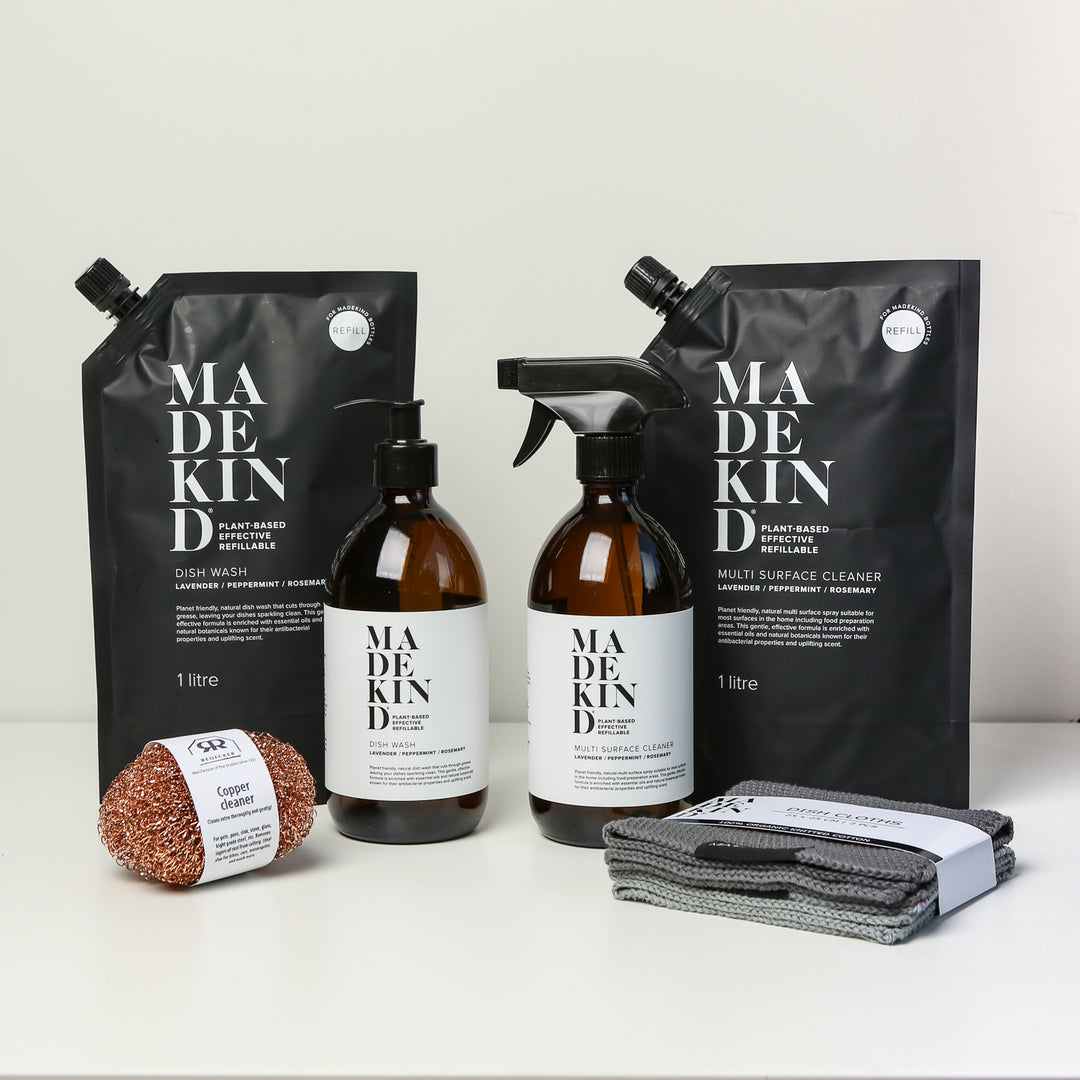 Photo of the MadeKind Kitchen Cleaning Kit; Multi Surface Cleaner and Dish Wash refills with 2 empty amber glass bottles, copper scourers and grey dishcloths