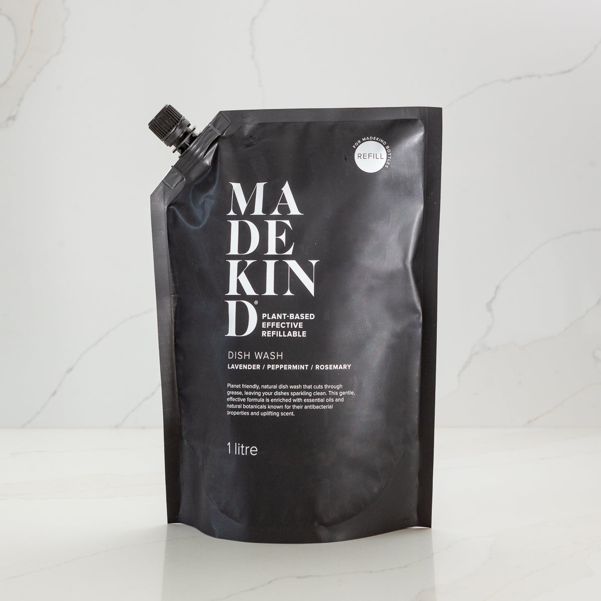 Black sustainable refill pouch with 'MadeKind' branding on a white kitchen background