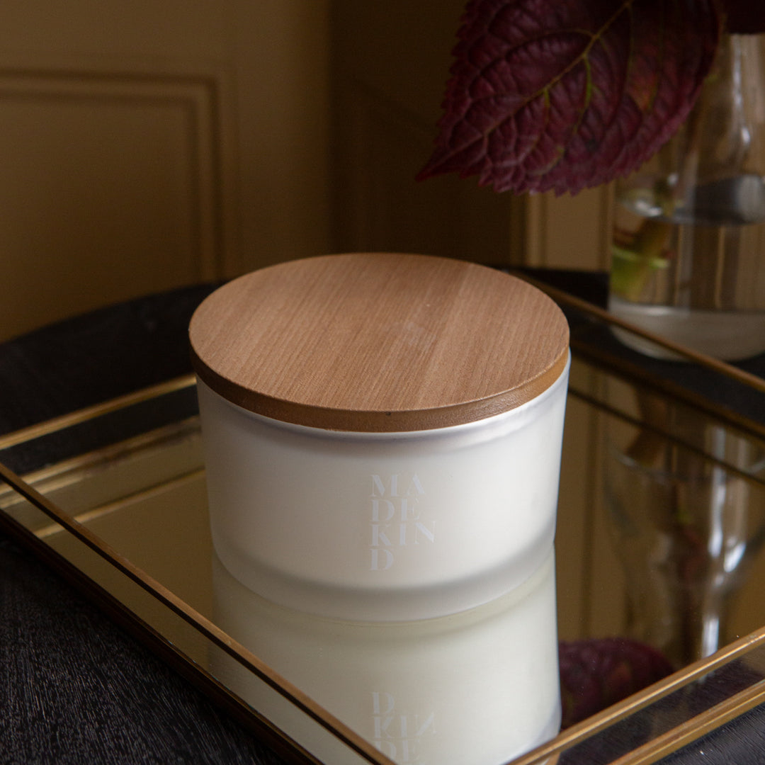 Three-wick sleep well candle in a white glass container with 'MadeKind' branding on the side. and with wooden lid