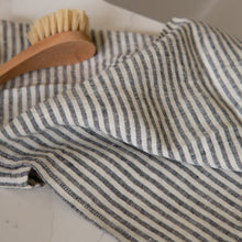 Load image into Gallery viewer, Photo of a woven linen grey striped tea towel with a natural bristle dish brush

