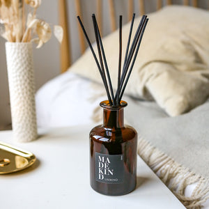 Photo of Aromatherapy reed diffuser with essential oils in amber glass jar on bedside table in bedroom