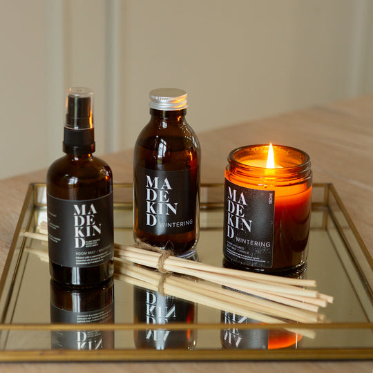 Three 'MADEKIND' products including bottles and a candle on a reflective surface.
