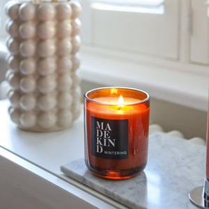 Wintering festive candle in amber glas jar on window ledge