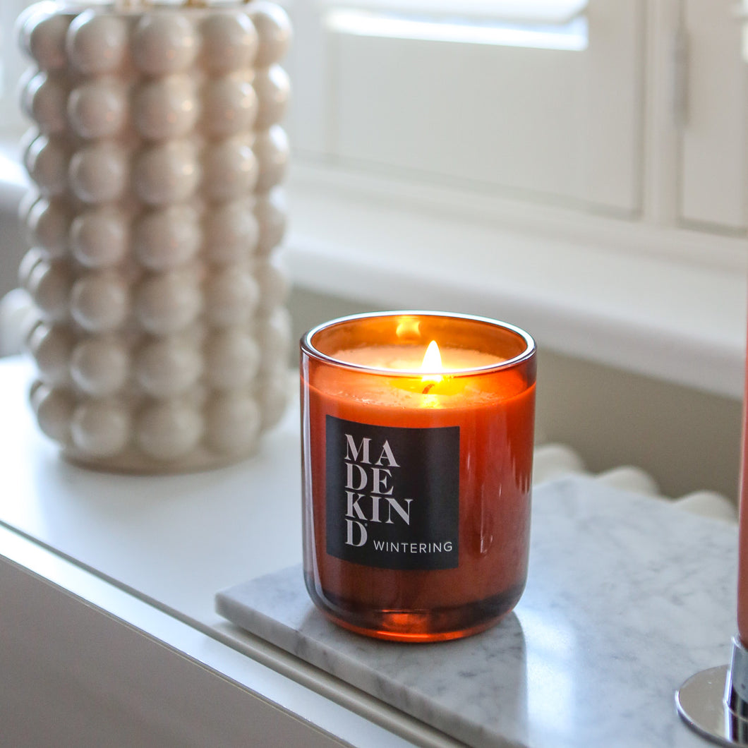 Wintering festive candle in amber glas jar on window ledge