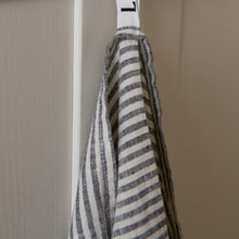 Load image into Gallery viewer, Photo of a woven linen grey striped tea towel hung from a hook
