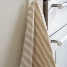 Load image into Gallery viewer, Photo of a woven linen white and beige striped tea towel hanging next to an oven in a kitchen
