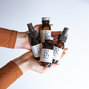 photo of hands holding 4 mini amber glass bottles of natural cleaning products