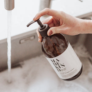 Photo of MadeKind Natural, eco friendly dish wash in 500ml amber glass bottle being pumped into a kitchen sink