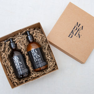 Photo of a brown luxury cardboard gift box containing a MadeKind natural hand wash and hand lotion in amber glass bottles