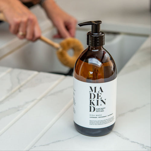 Photo of a MadeKind Natural, eco friendly dish wash in 500ml amber glass bottle next to a kichen sink