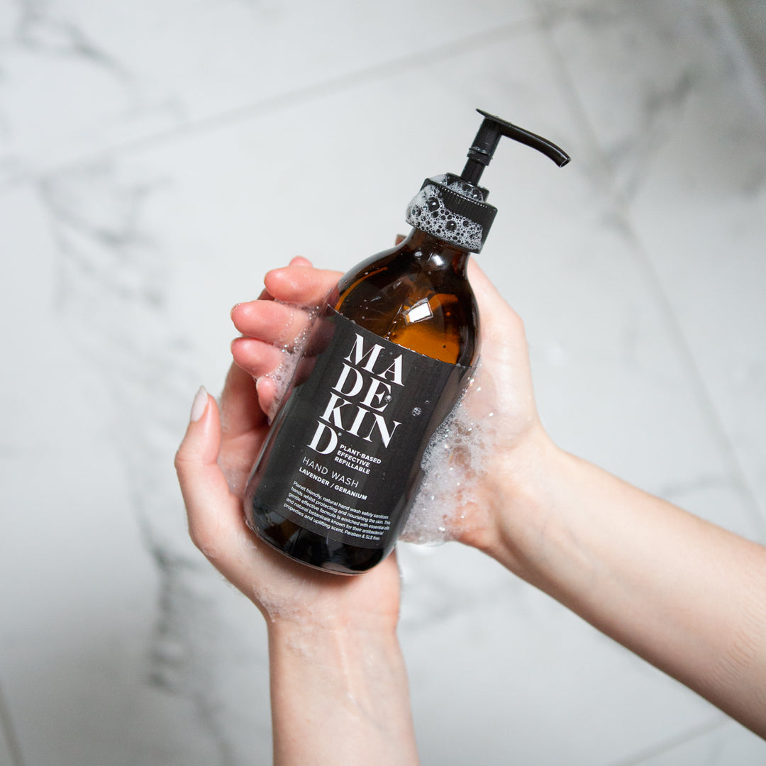 Photo of the Madekind natural, gentle hand wash in an amber glass bottle, held in someone's soapy hands